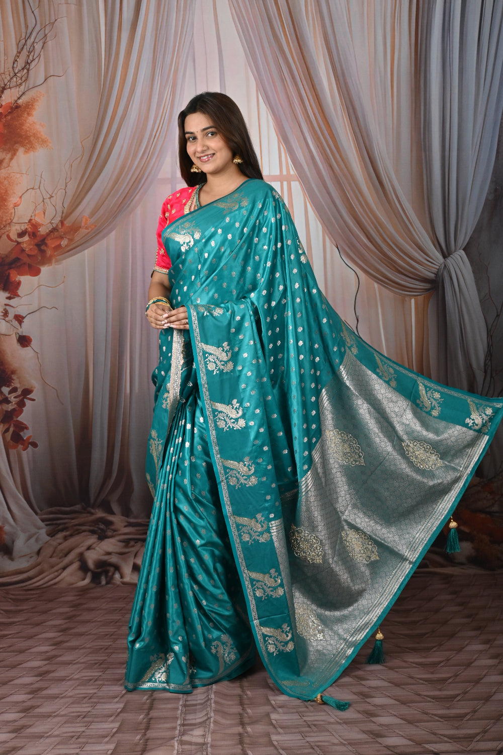Woman wearing a teal saree with a white blouse against a draped curtain background