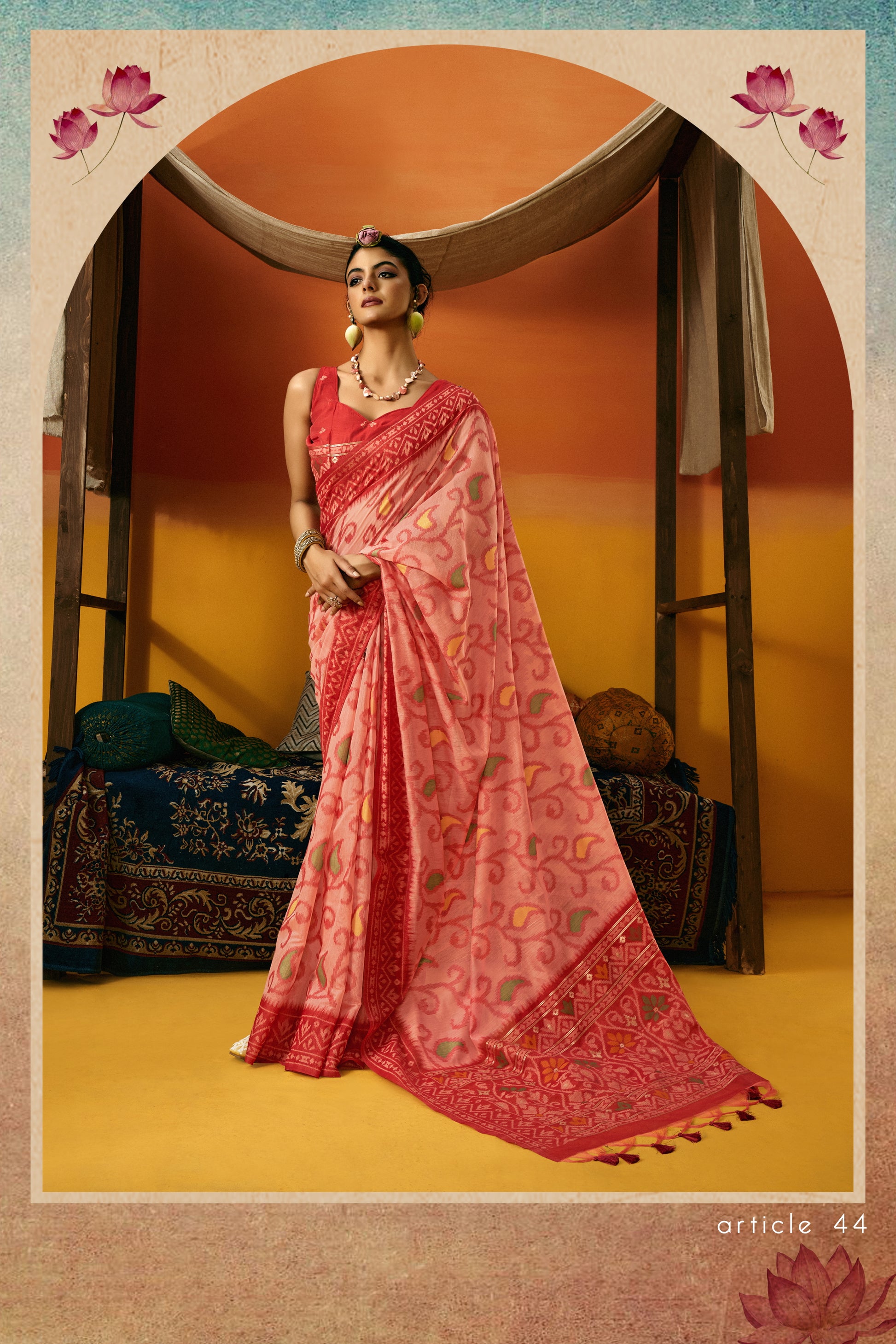 Woman in a pink saree standing in a decorated room with lotus flowers.