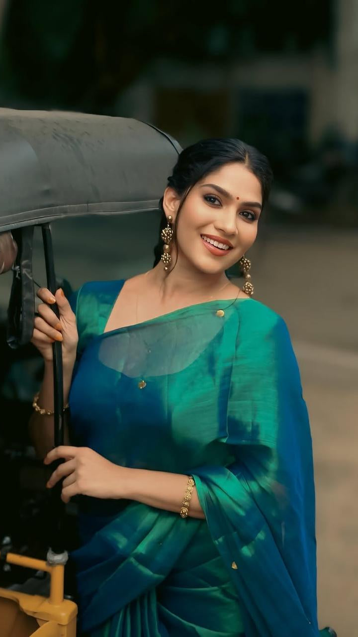 Woman in a green saree holding an umbrella outdoors
