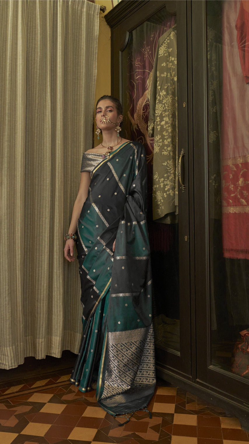 Woman in a saree standing in front of a wardrobe with various clothes on display.