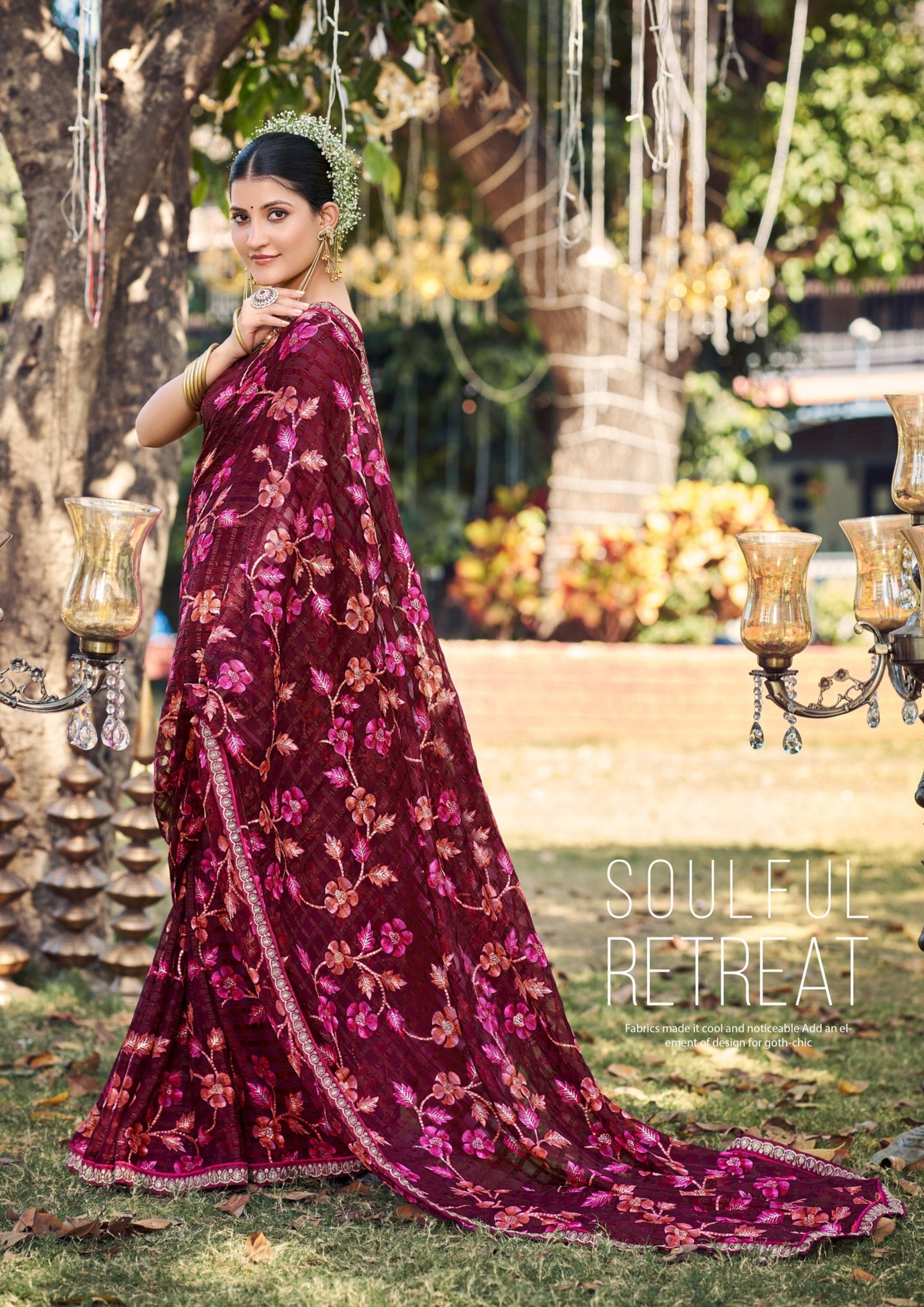 Woman in a burgundy floral dress standing outdoors with decorative lights and plants.