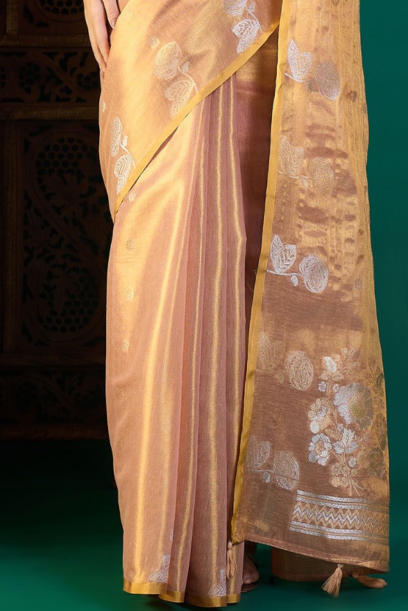 Woman wearing a gold saree with a decorative wooden panel in the background