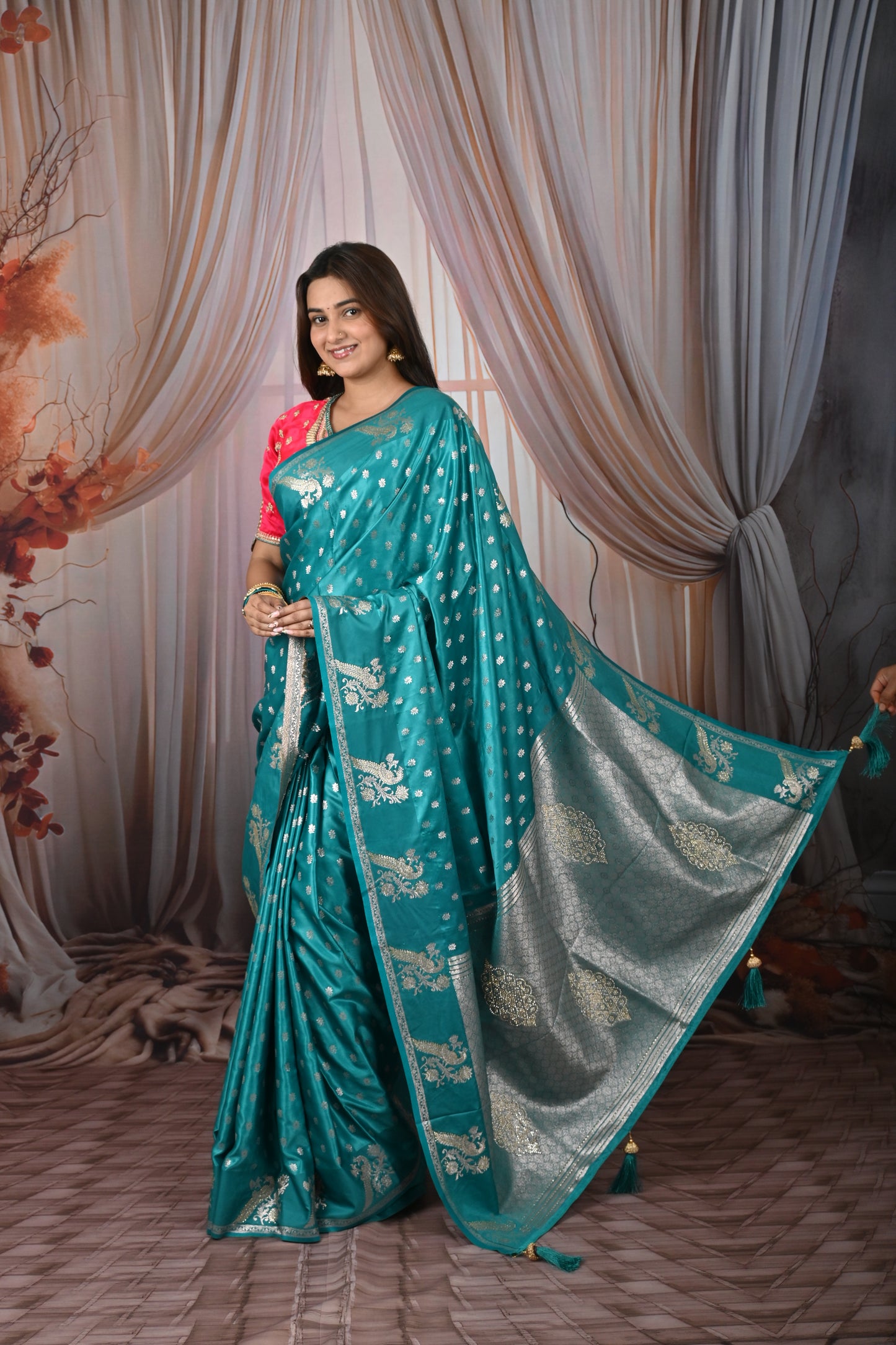 Woman wearing a teal saree with a white blouse against a draped curtain background