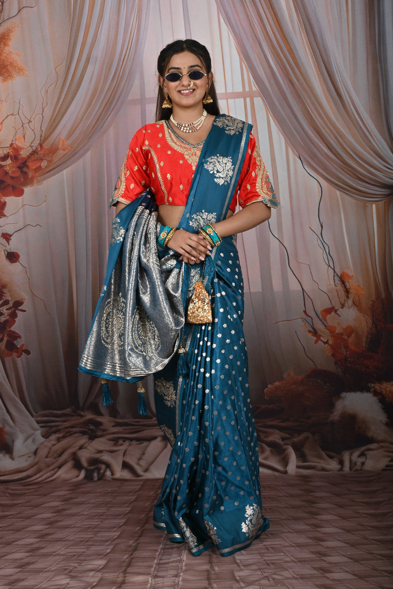 Woman in a blue saree with a red blouse against a decorative backdrop