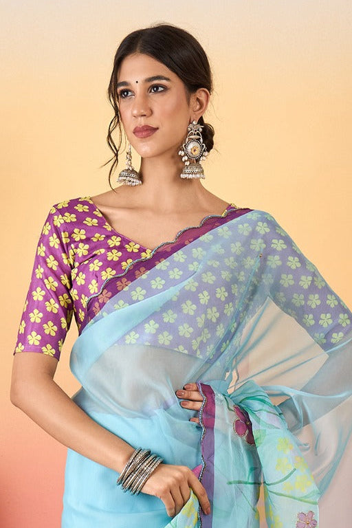 Woman wearing a light blue floral saree with a pink blouse against a gradient background