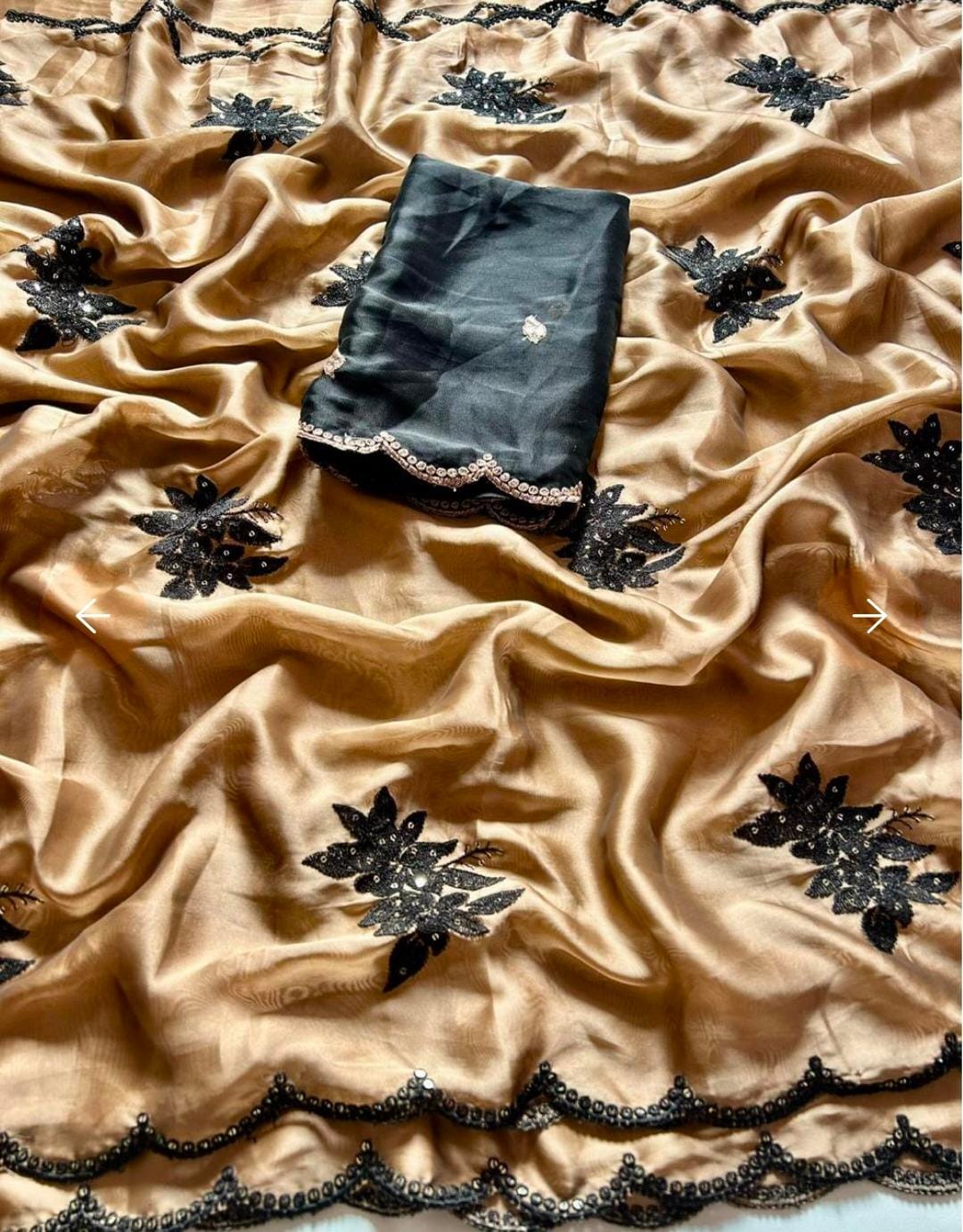 Black saree with floral patterns on a beige fabric background
