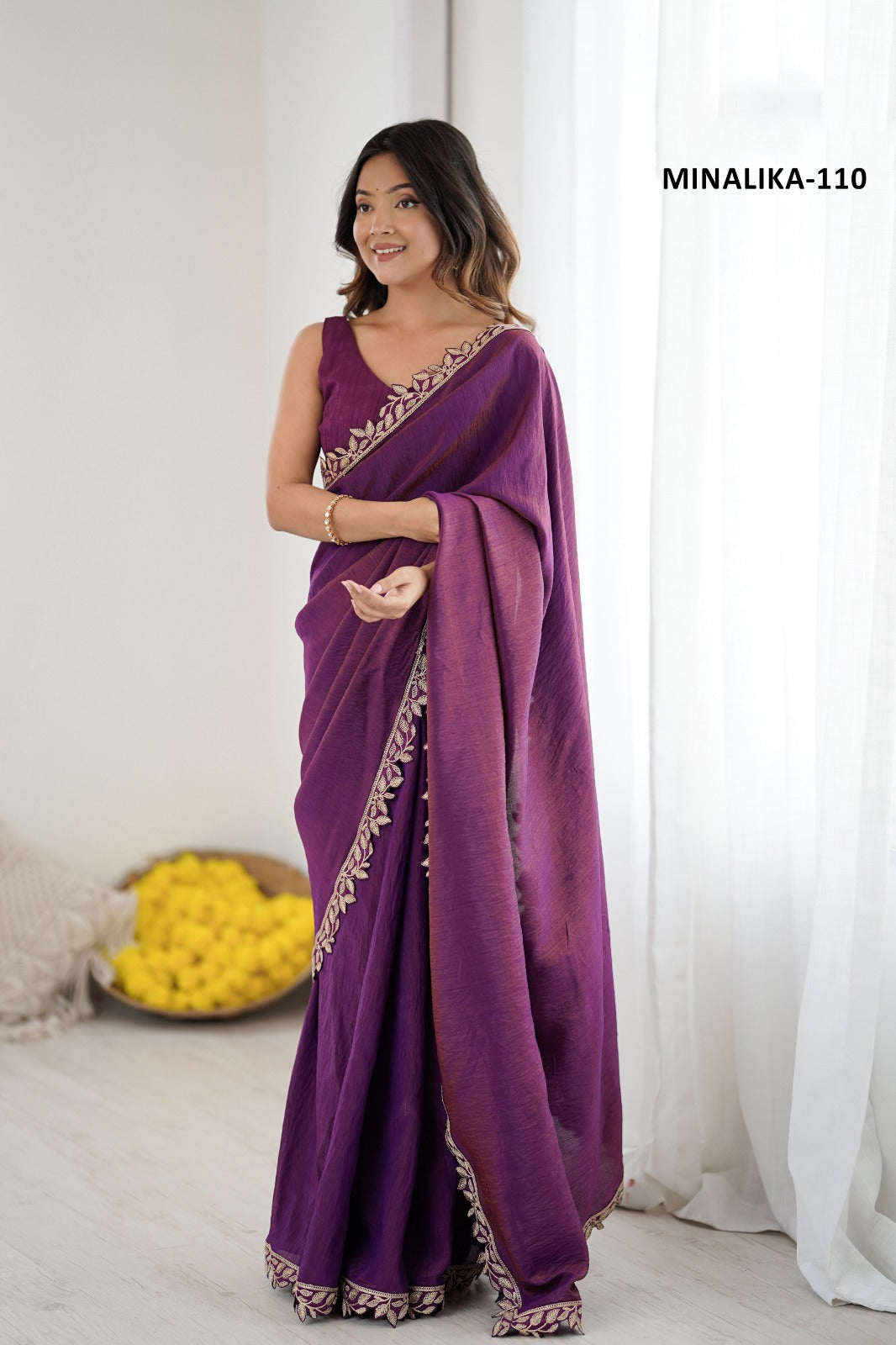 Woman wearing a purple saree with gold border in a bright room