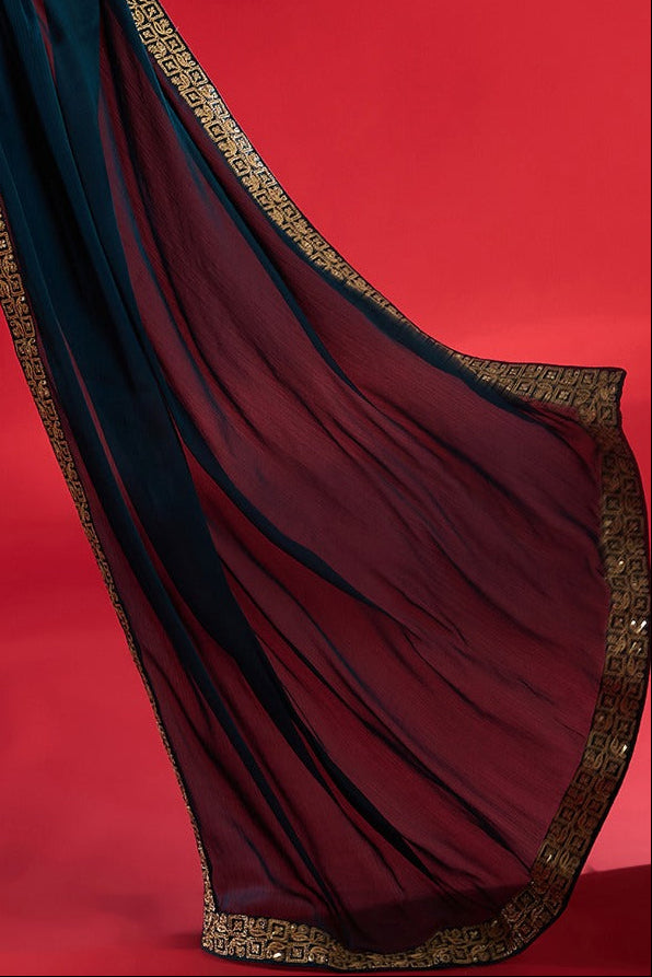 Woman wearing a blue saree with gold border on a red background