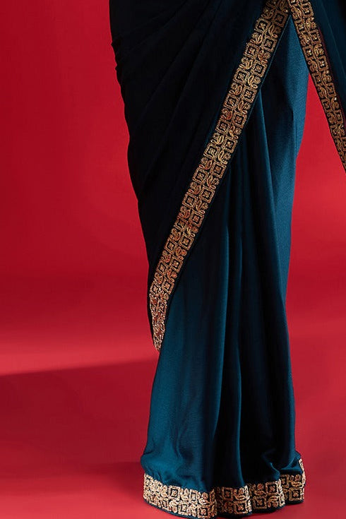 Woman wearing a blue saree with gold border on a red background