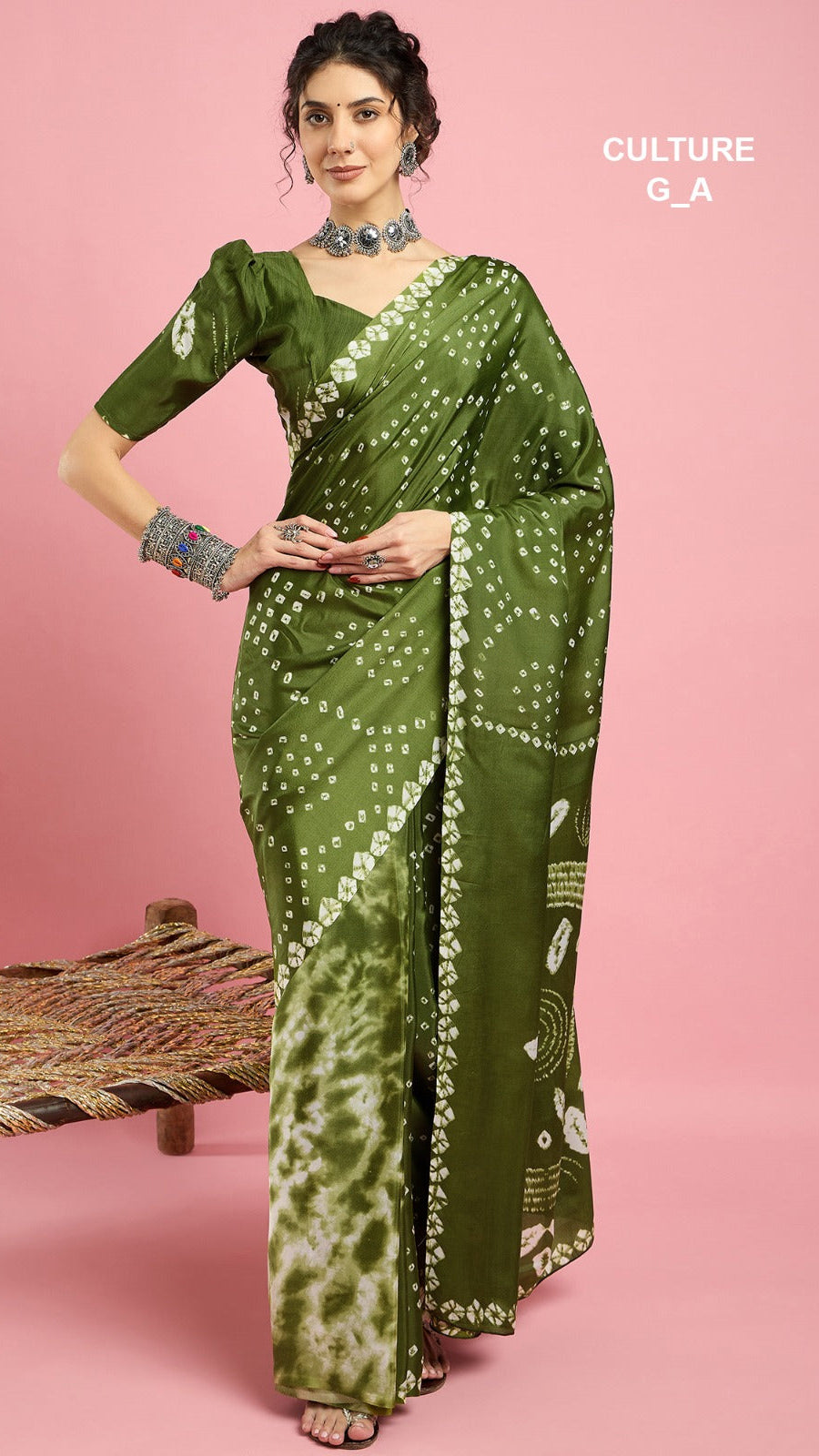 Woman wearing a green saree with white patterns on a pink background
